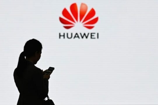 Silhouette d'une femme avec smartphone devant le logo Huawei