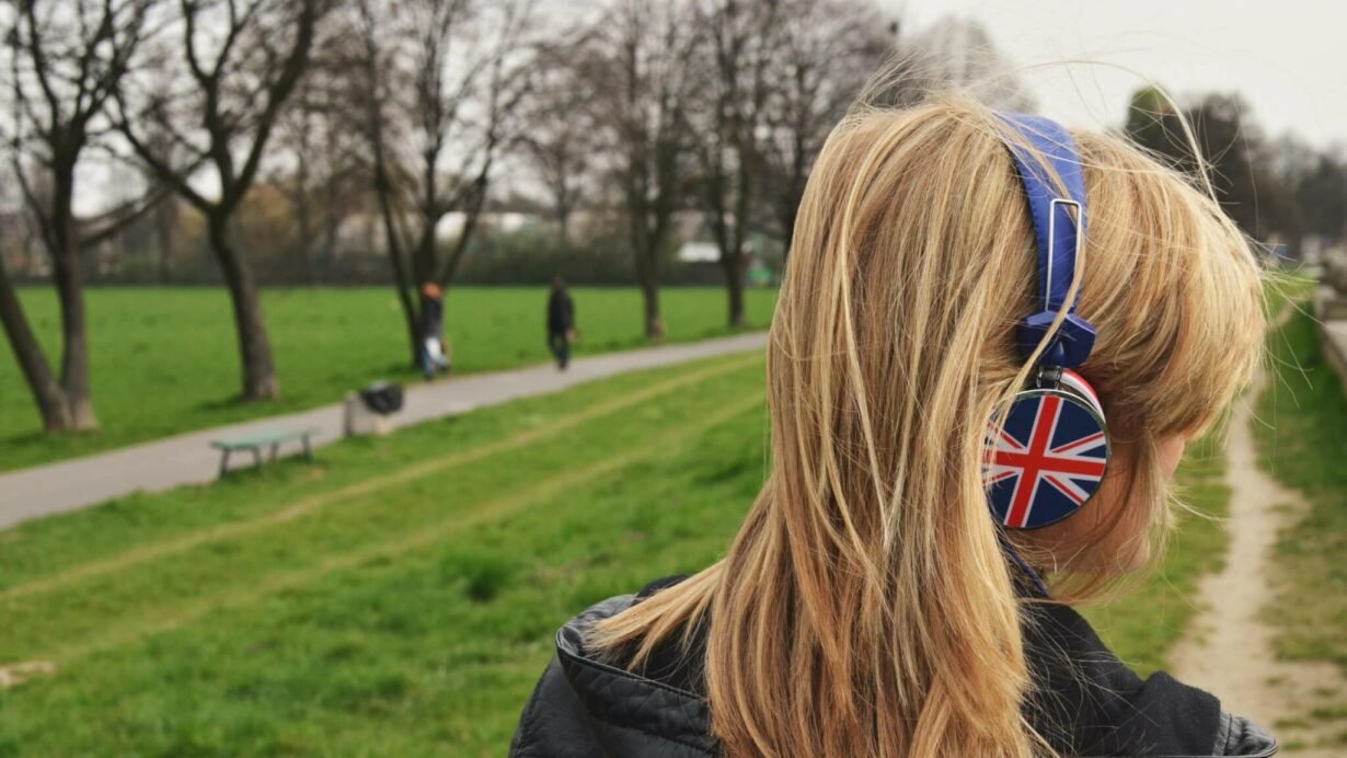 Femme écoutant de la musique avec un casque Union Jack dans un parc