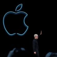 Homme saluant devant le logo lumineux d'Apple sur fond noir