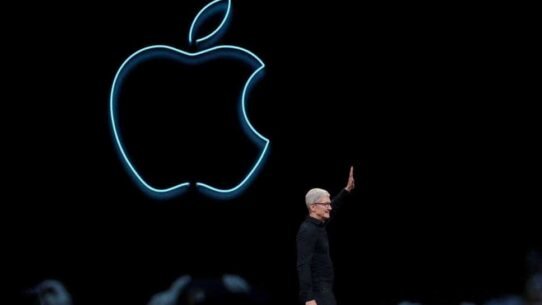 Homme saluant devant le logo lumineux d'Apple sur fond noir