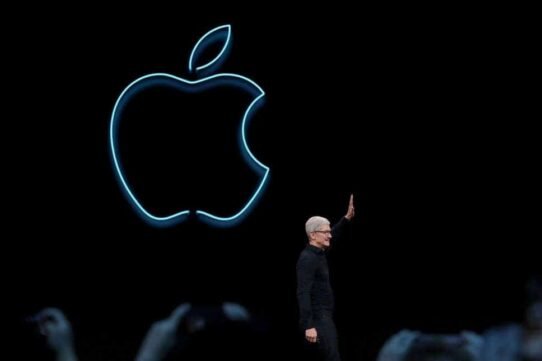 Homme saluant devant le logo lumineux d'Apple sur fond noir