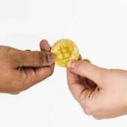Deux mains échangent une pièce de bitcoin dorée
