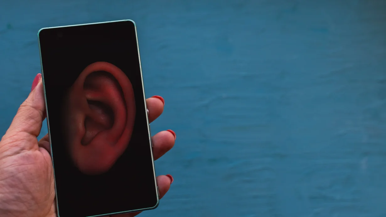 Une main utilisant un smartphone avec des icônes d'espionnage