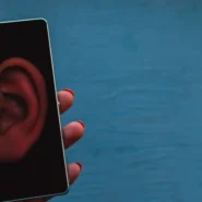 Une main utilisant un smartphone avec des icônes d'espionnage