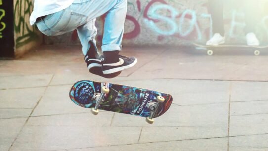Skateur effectuant un saut avec une planche colorée devant un mur graffité