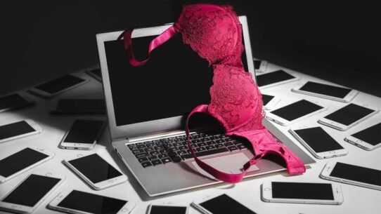 Ordinateur portable avec soutien-gorge rose et téléphones autour