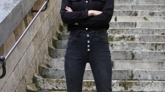 Femme en noir posant sur un escalier en pierre