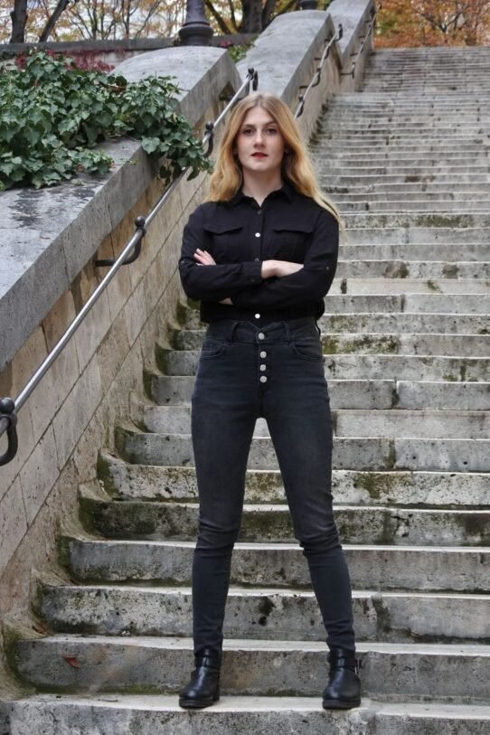 Femme en noir posant sur un escalier en pierre