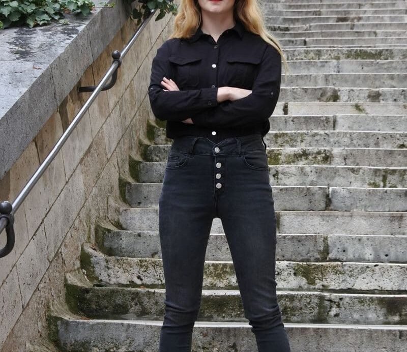 Femme en noir posant sur un escalier en pierre