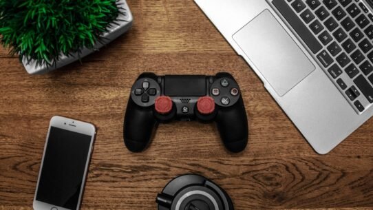 Manette de jeu, smartphone, casque et ordinateur portable sur un bureau