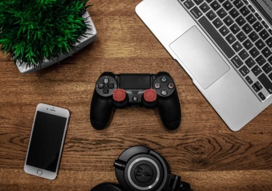 Manette de jeu, smartphone, casque et ordinateur portable sur un bureau