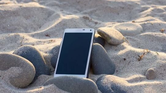 Smartphone posé sur du sable entouré de galets