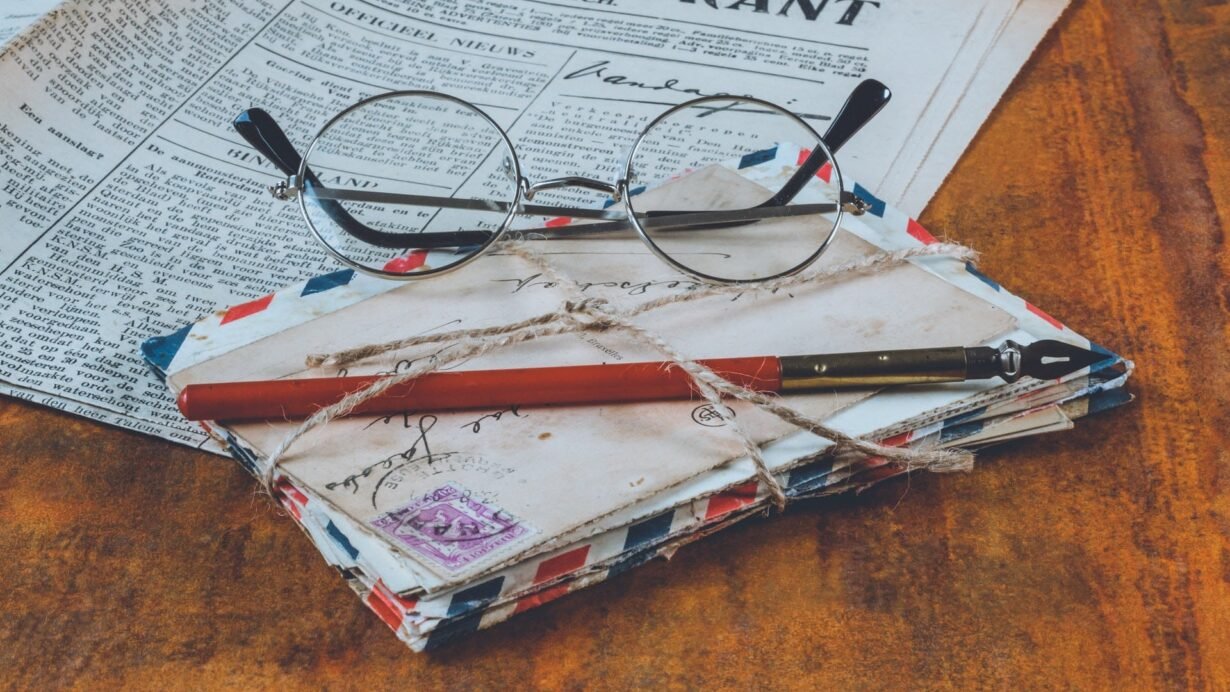 Lunettes, lettres anciennes et journal sur une table en bois
