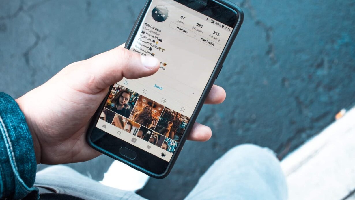Main tenant un smartphone affichant un profil Instagram