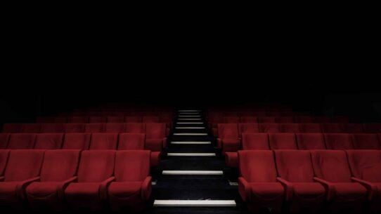 Rangées de sièges rouges dans une salle de cinéma sombre