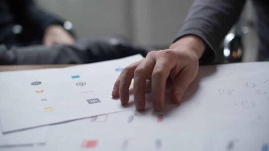 Main posée sur des feuilles avec des ébauches de logos