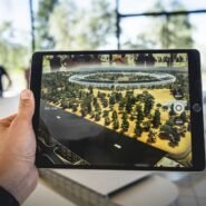 Main tenant une tablette affichant un modèle 3D d'un bâtiment circulaire
