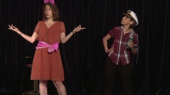 Deux femmes sur scène dans un sketch humoristique avec accessoires