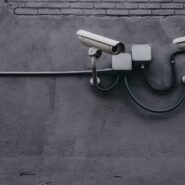 Deux caméras de surveillance fixées sur un mur gris