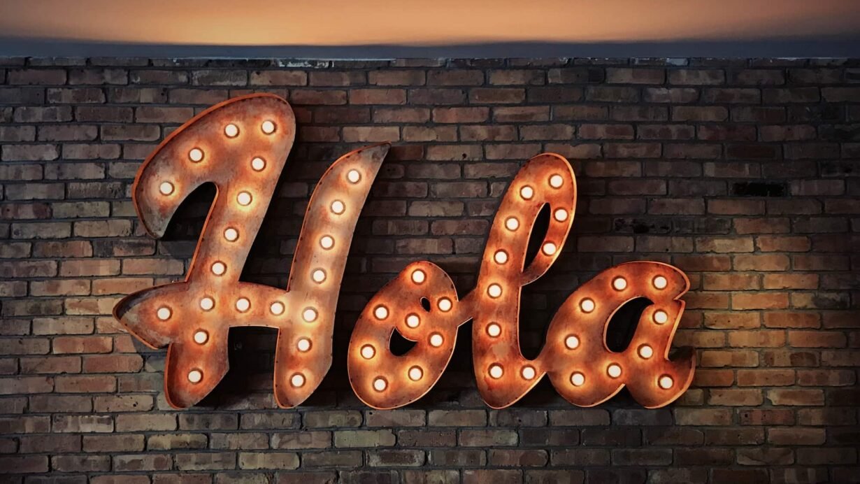 Enseigne lumineuse Hola sur un mur de briques