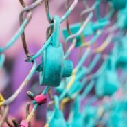 Cadenas turquoise accroché à une clôture métallique colorée