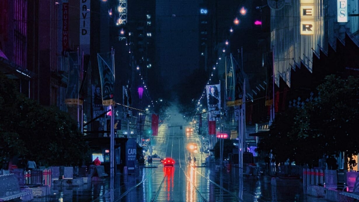 Rue nocturne avec lumières néon et reflets sur le sol mouillé