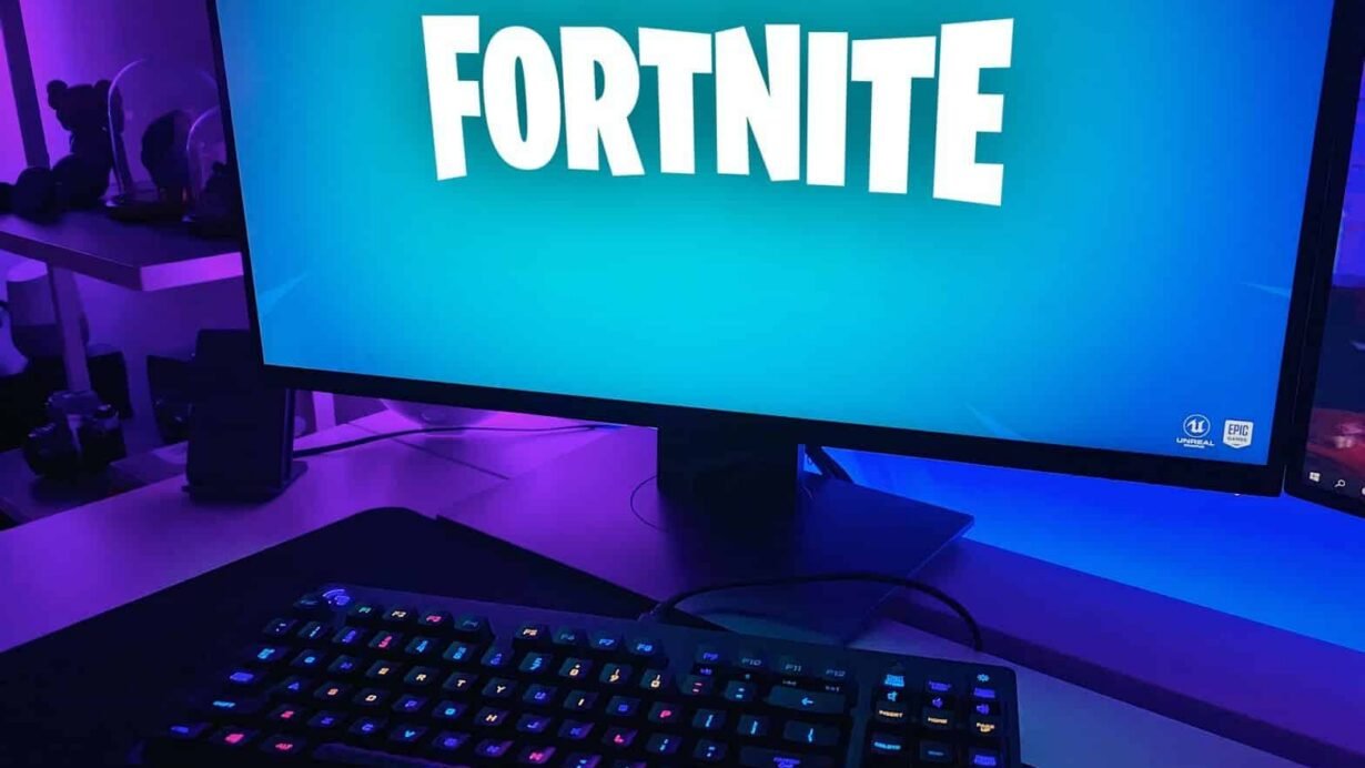 Écran d'ordinateur affichant Fortnite avec un clavier illuminé