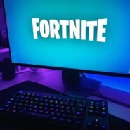 Écran d'ordinateur affichant Fortnite avec un clavier illuminé