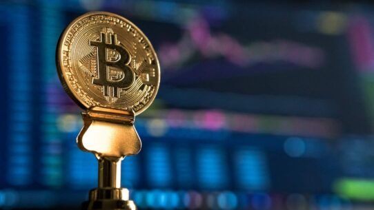 Pièce en or de Bitcoin devant un écran d'ordinateur