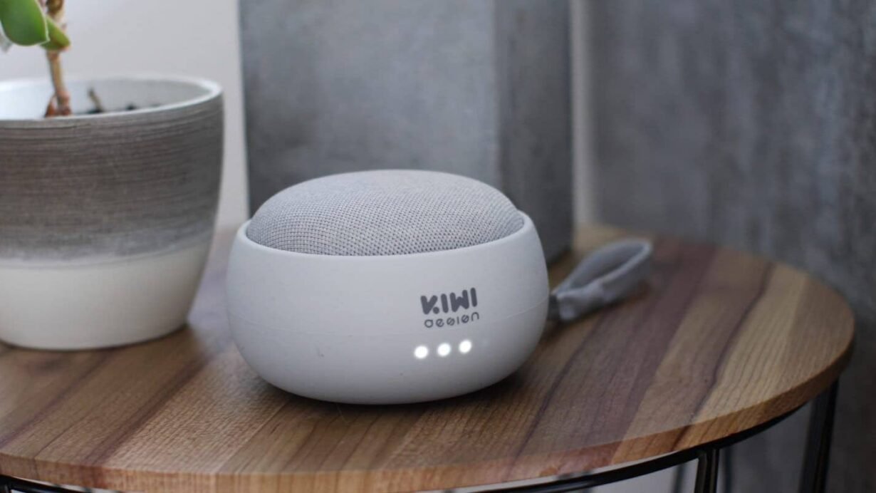 Haut-parleur intelligent sur une table en bois à côté d'une plante