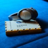 Casque audio gris posé sur un livre jaune sur un canapé bleu