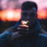 Main tenant un briquet allumé devant un fond crépusculaire