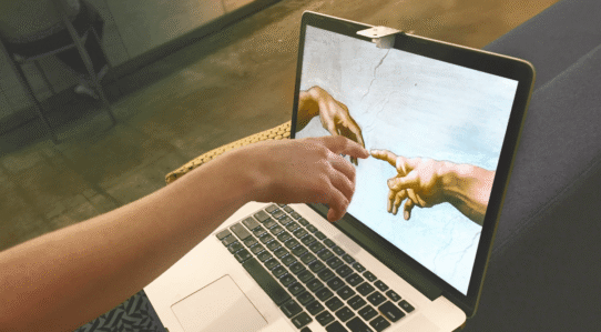 Main touchant l'écran d'un ordinateur affichant une œuvre d'art