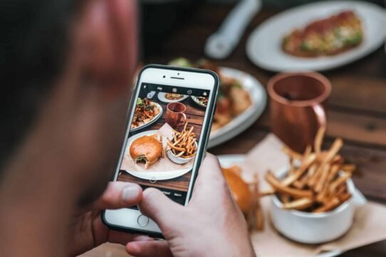 Personne prenant une photo de plats gourmands avec un smartphone