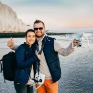 Couple souriant sur la plage avec un drone en main