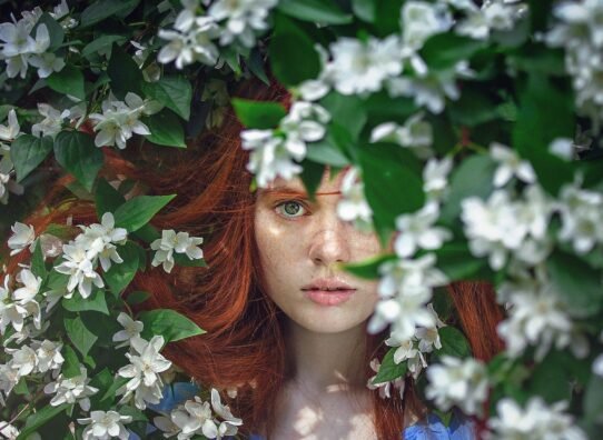 Visage de femme rousse entouré de fleurs blanches