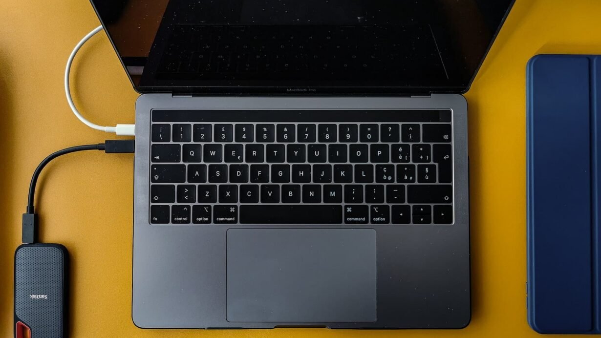 Ordinateur portable connecté à un disque dur externe sur une table jaune