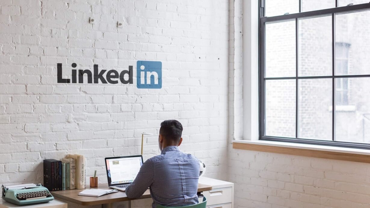 Homme travaillant sur un ordinateur portable dans un bureau avec logo LinkedIn