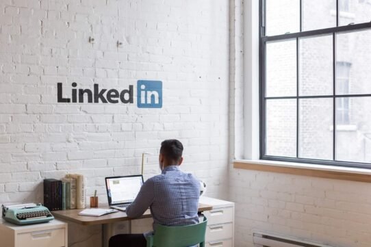 Homme travaillant sur un ordinateur portable dans un bureau avec logo LinkedIn