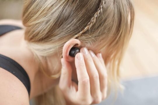 Femme blonde ajustant un écouteur sans fil dans son oreille
