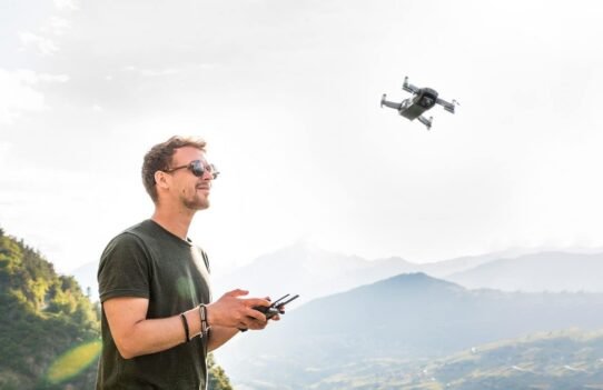 Homme contrôlant un drone dans un paysage de montagne