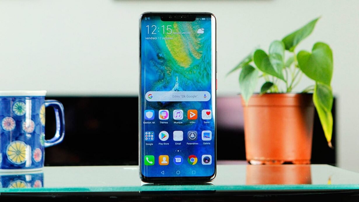 Smartphone moderne posé sur une table près d'une plante