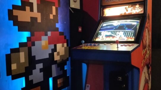 Borne d'arcade rétro et mur décoré d'un personnage pixelisé