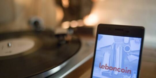 Smartphone avec Leboncoin et platine vinyle en arrière-plan
