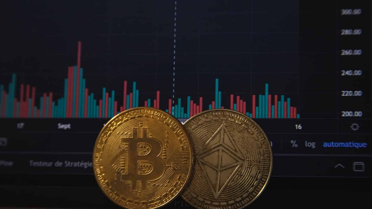 Pièces de Bitcoin et Ethereum devant un graphique boursier
