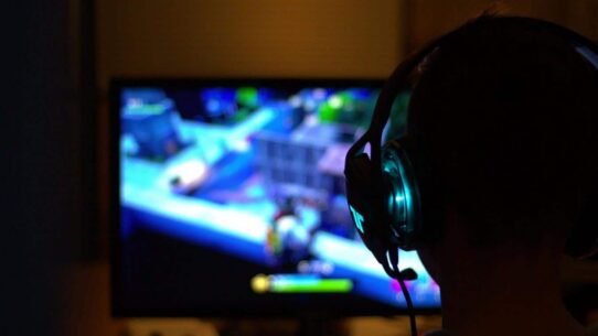 Personne portant un casque devant un écran de jeu vidéo