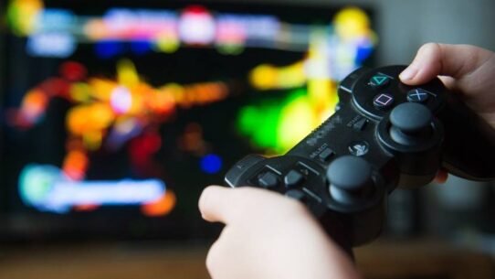 Gros plan d'une manette de jeu devant un écran coloré