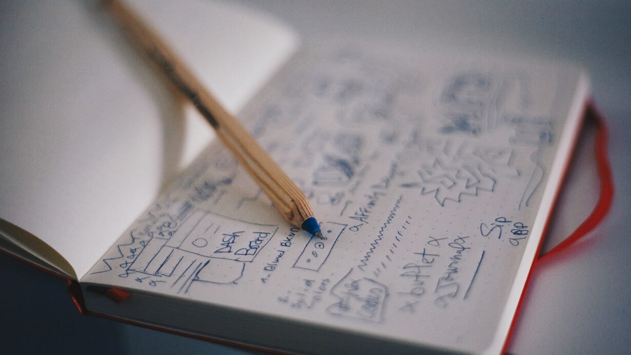 Carnet de notes ouvert avec croquis et stylo en bois
