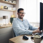 Homme souriant devant un ordinateur dans un bureau à domicile
