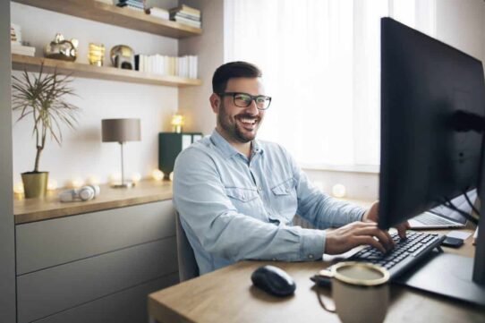 Homme souriant devant un ordinateur dans un bureau à domicile